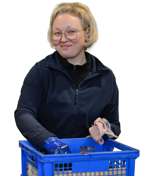 Eine Person hält einen blauen Kunststoffkorb mit mehreren brünierten Metallteilen und einem Handschuh.